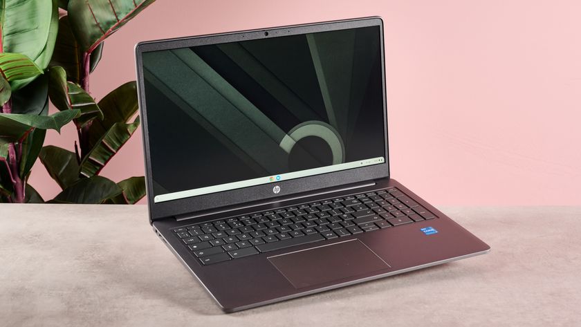 HP Chromebook Plus 15.6-inch on table with pink wall and plant in background 