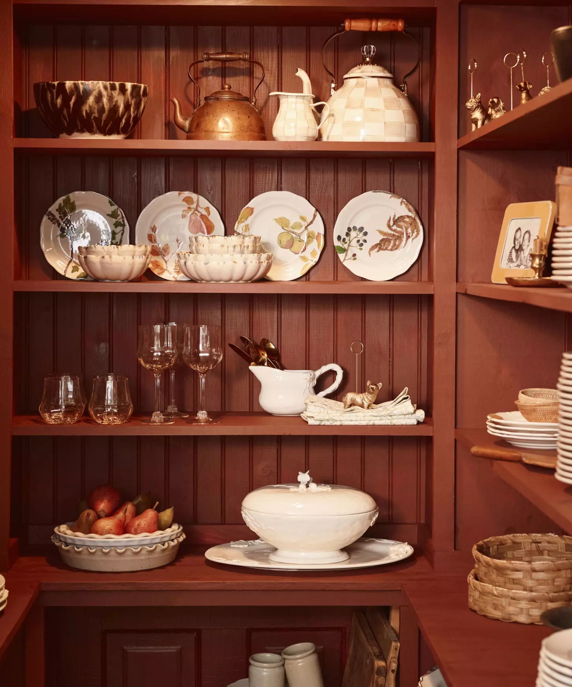 burgundy burnt orange kitchen pantry with shelves filled with thanksgiving, fall themed plates, serveware and amber colored glassware