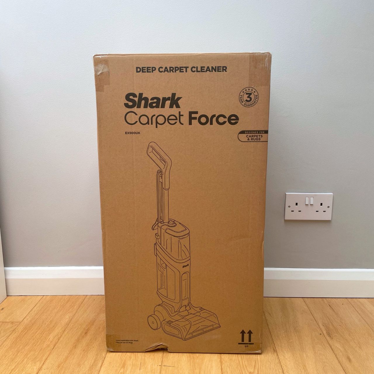 Shark CarpetForce Upright Carpet Cleaner box sitting on wooden floor in front of a grey wall