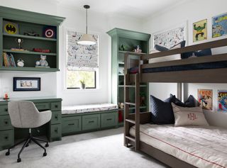 A kids bedroom with a built in green space for desk, storage and window seat