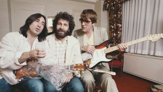 Lol Creme (left) and Kevin Godley (centre) from 10CC with English comedian Peter Cook (1937-1995), 1977. Cook is holding a guitar fitted with a prototype Gizmotron, (aka The Gizmo), an effects device invented by Godley and Cream, which uses serrated wheels to produce a bowing effect on guitar strings. Cook contributed to Godley and Creme's concept album 'Consequences', which was intended to showcase the Gizmotron. The device was later marketed commercially, but proved unsuccessful.