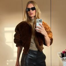 Rosie wears a suede jacket, brown tee, and leather pants.