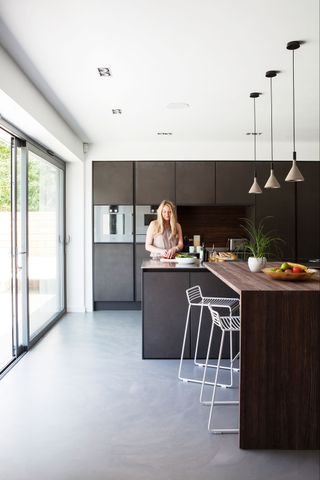 modern handleless kitchen with wooden breakfast bar and a trio of pendant lights