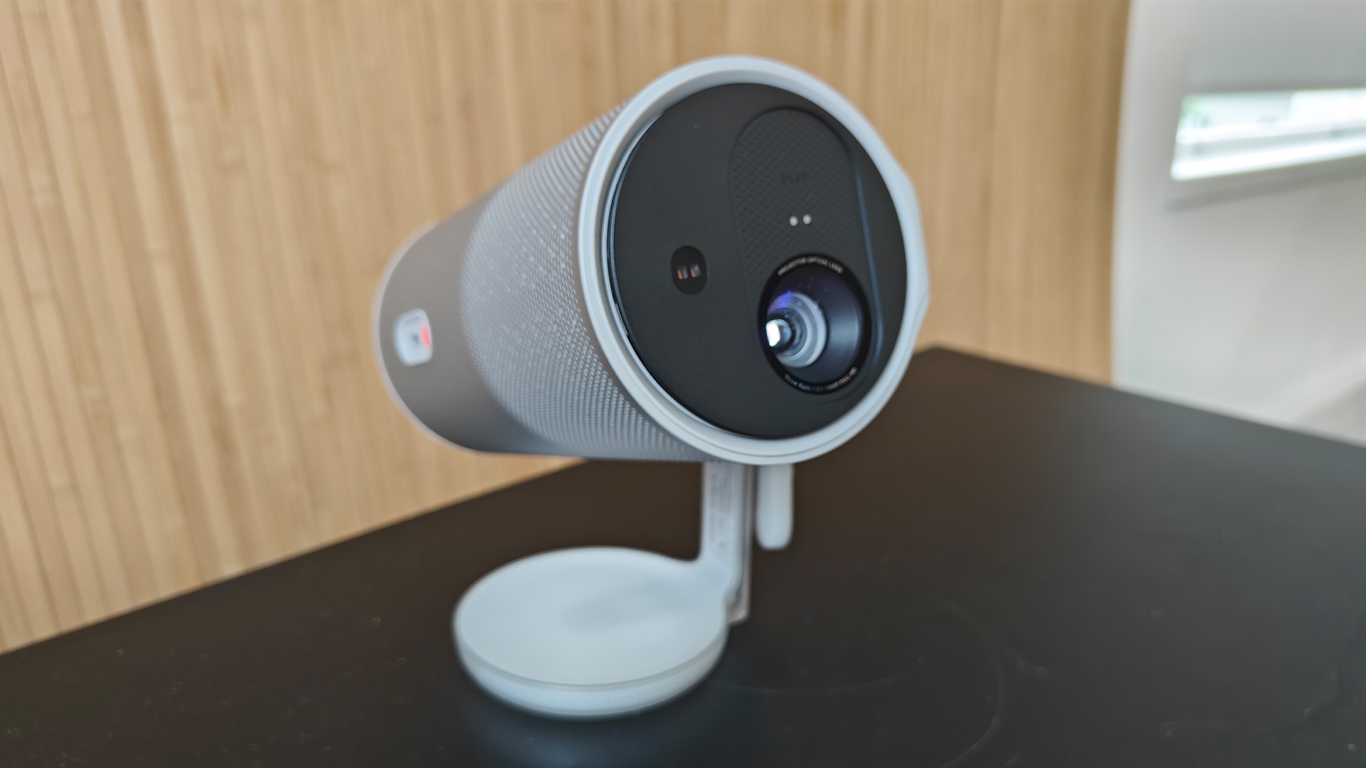 Xgimi MoGo 4 portable projector on black surface against wooden wall