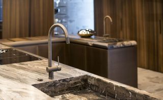 A close-up of a tap and the U shaped island kitchen.