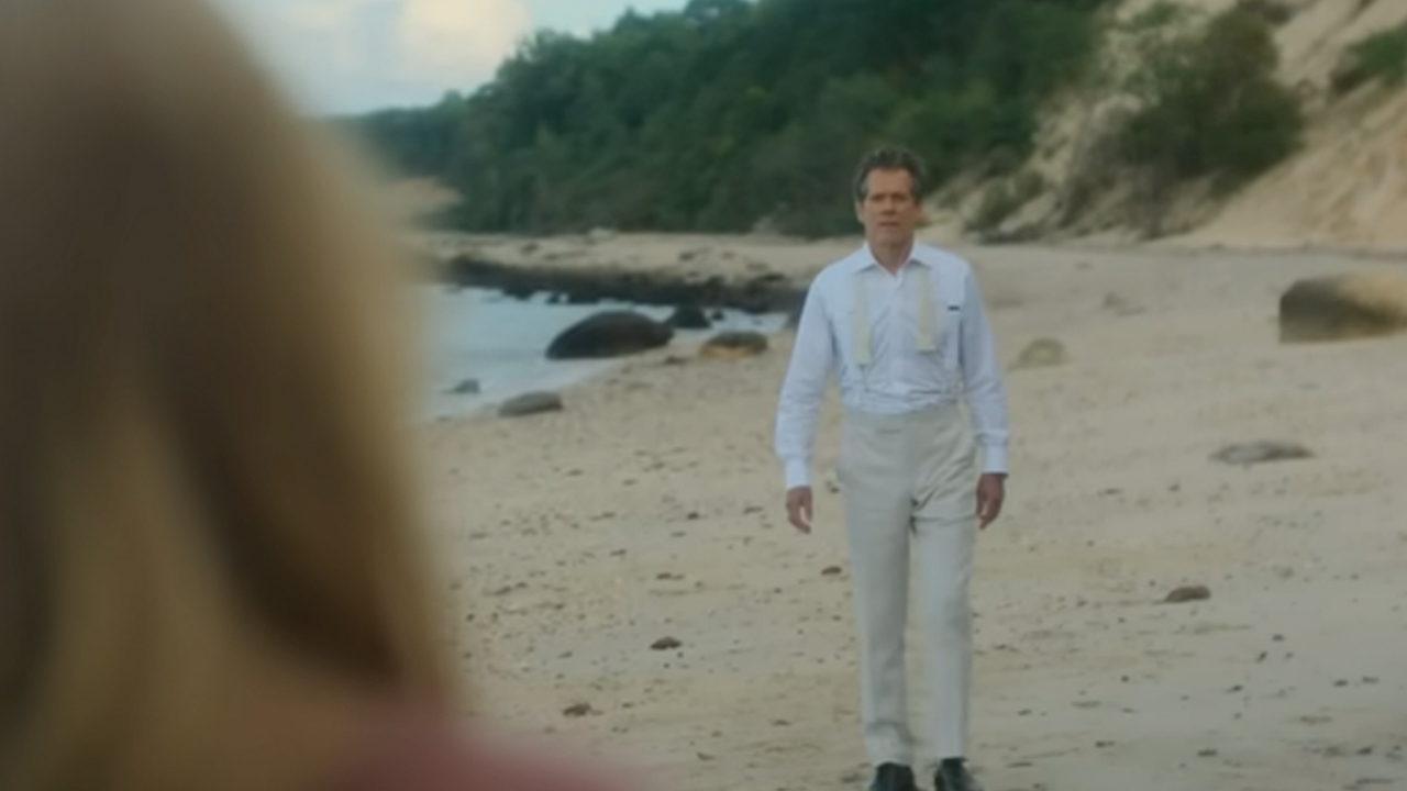 Kevin Bacon in a white tuxedo on the beach in Sirens