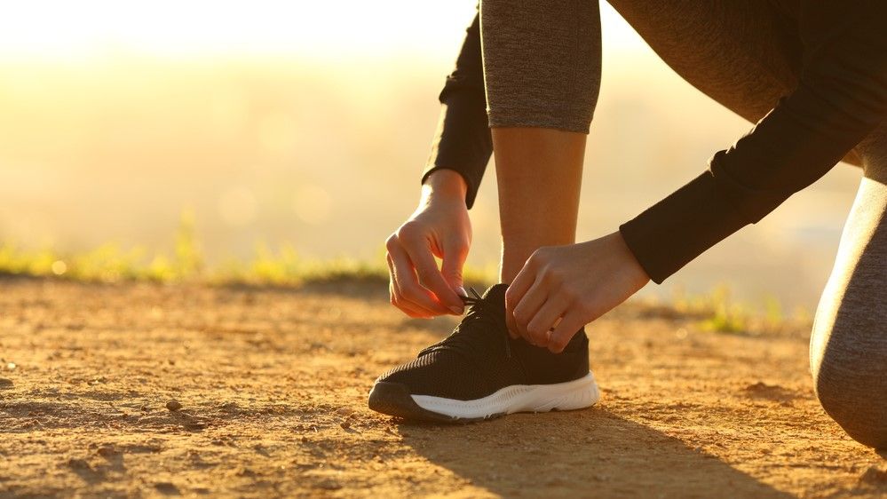 a photo of a woman lacing up running shoes