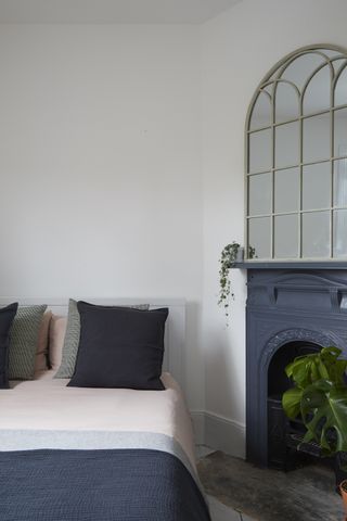 A bedroom with a fireplace painted in a charcoal grey