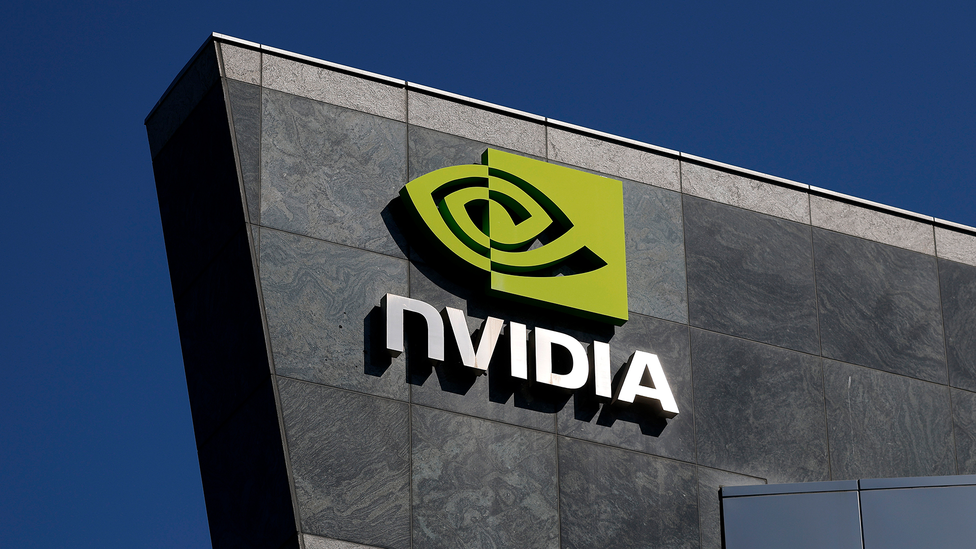 Nvidia logo and branding pictured on the side of the company's headquarters in Santa Clara, California, with clear blue skies pictured in background.
