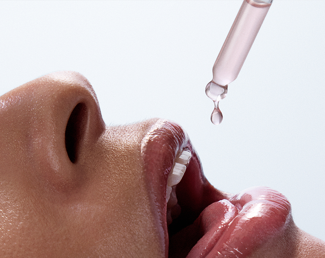 Woman ingesting Sakara's Cell Reset liquid supplement from a tincture.