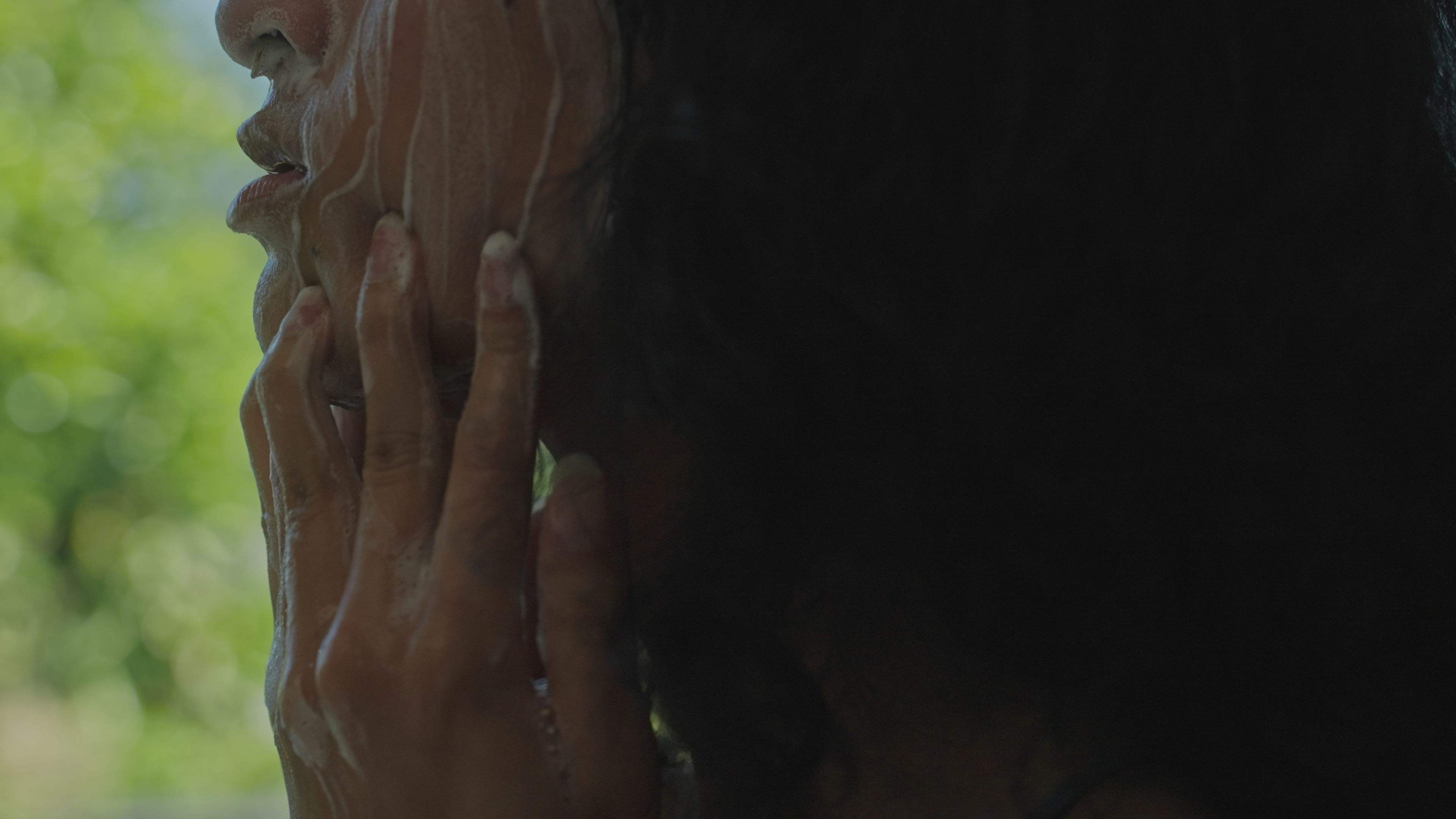 A woman runs fingers down her face, which is covered in foam