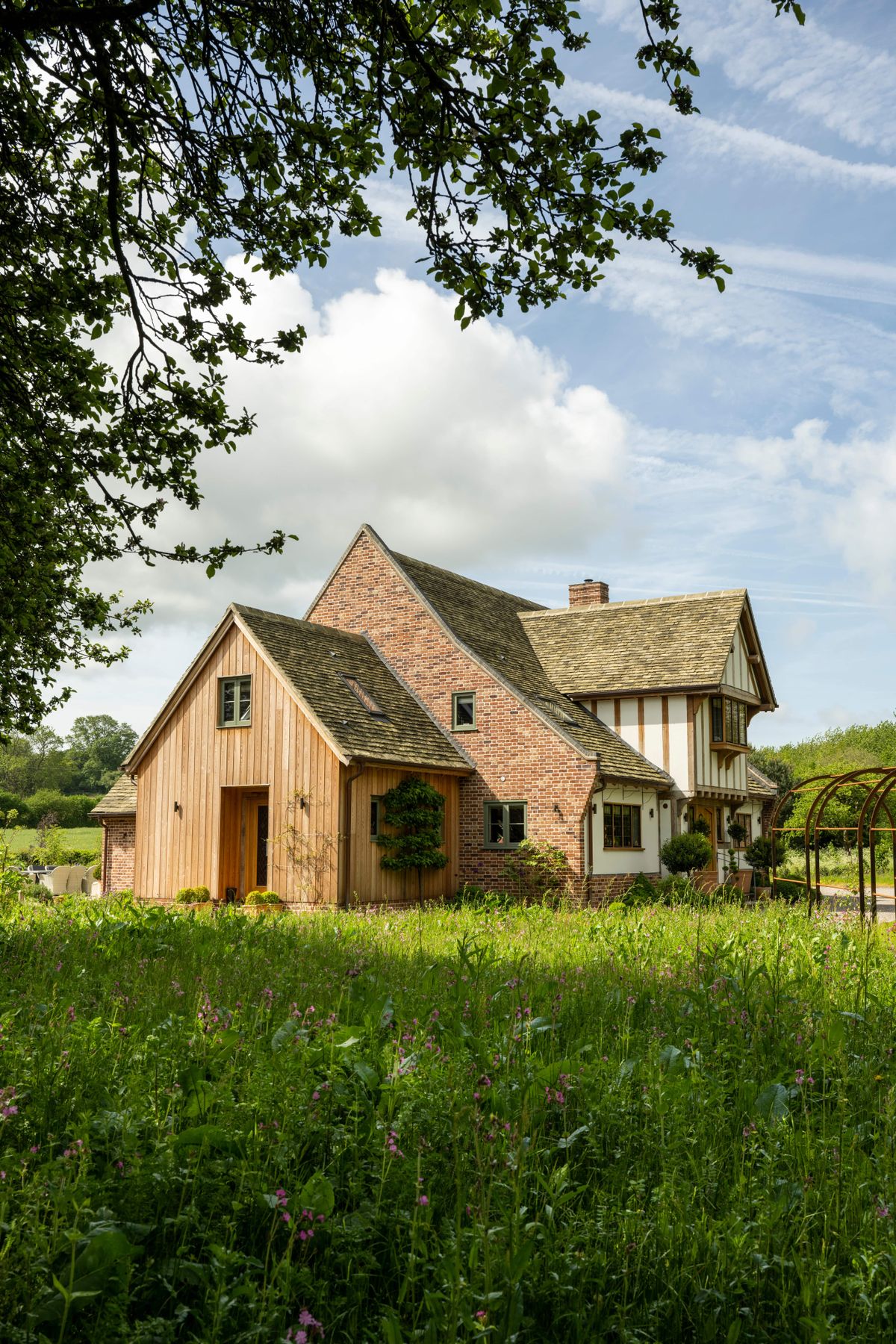 An oak framed home with wood cladding surrounded by a lush country garden