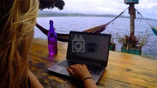 Woman working on laptop on wooden platform overlooking the sea