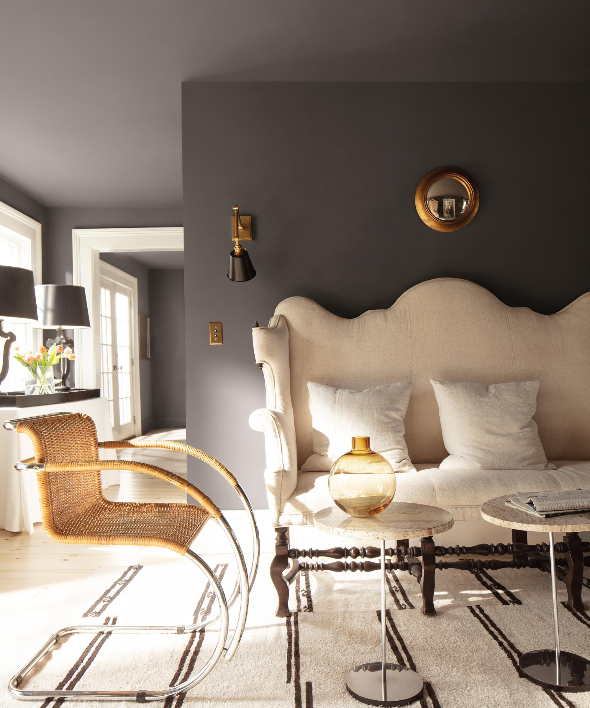 a living room with a large white couch, a rattan accent chair, two drink tables, and walls and ceiling painted with Benjamin Moore&#039;s Silhouette