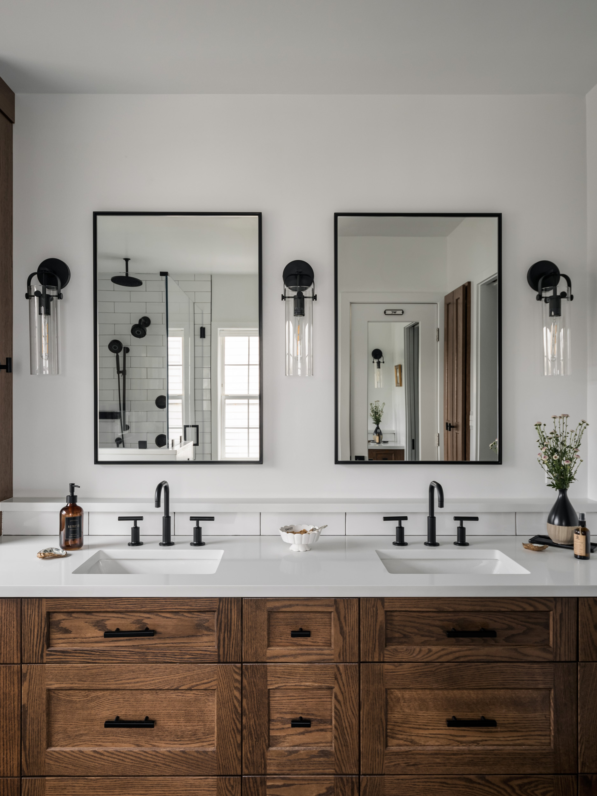 A bathroom with a double wooden vanity with white countertops