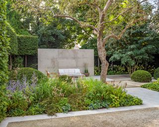 vertical stone slab garden divider behind seating area and planted beds set in hard landscaping