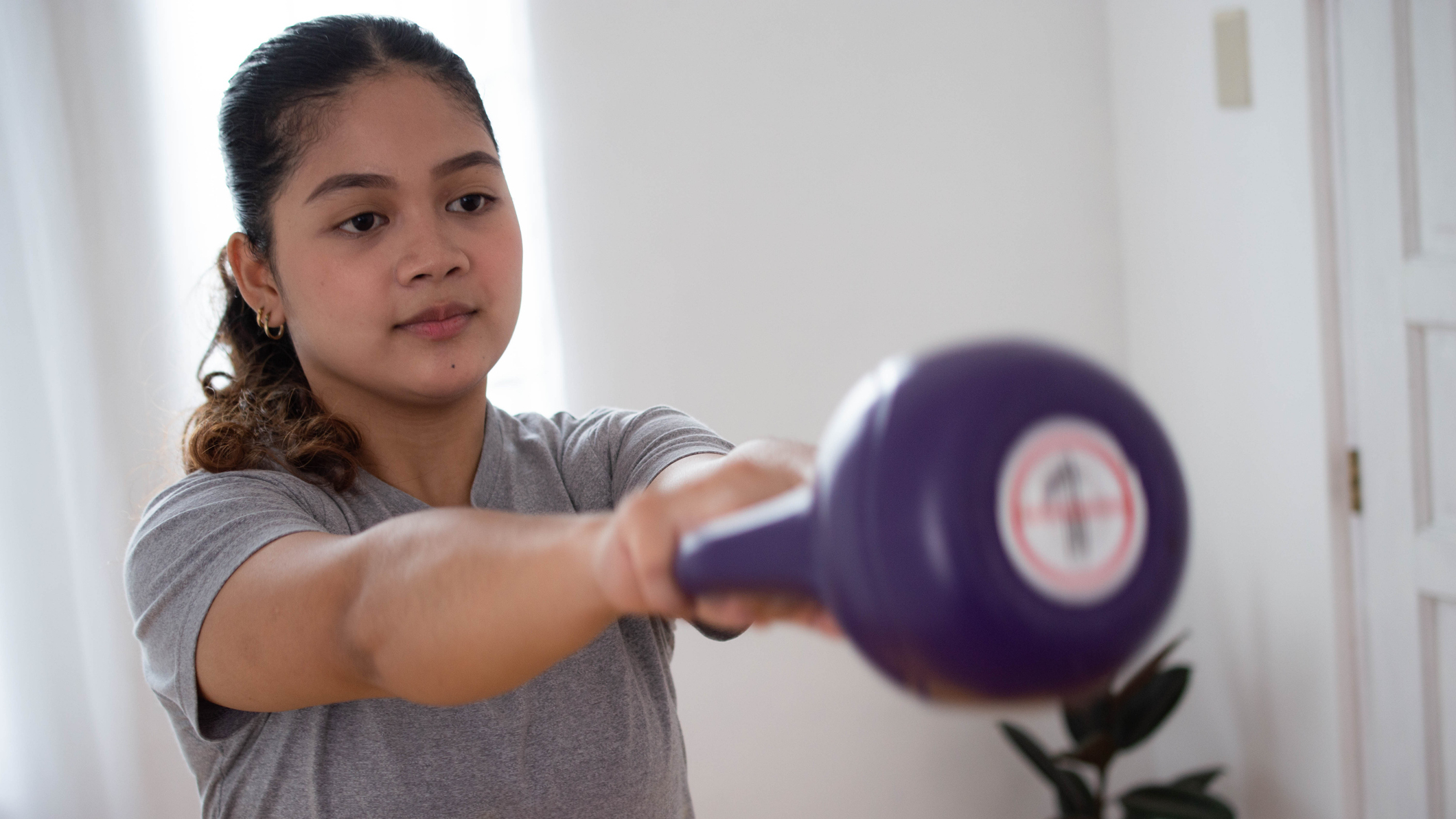 Woman performing kettlebell swing in a domestic setting
