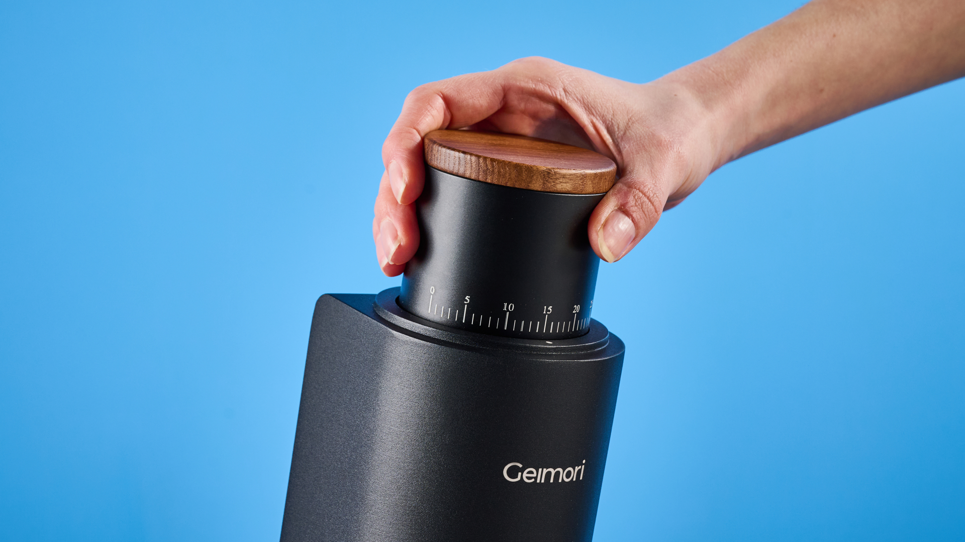 the wirsh geimori gu38 coffee grinder in black with a walnut hopper lid photographed against the blue tom's guide background