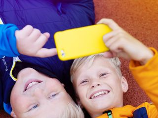 To barn med en gul mobiltelefon.
