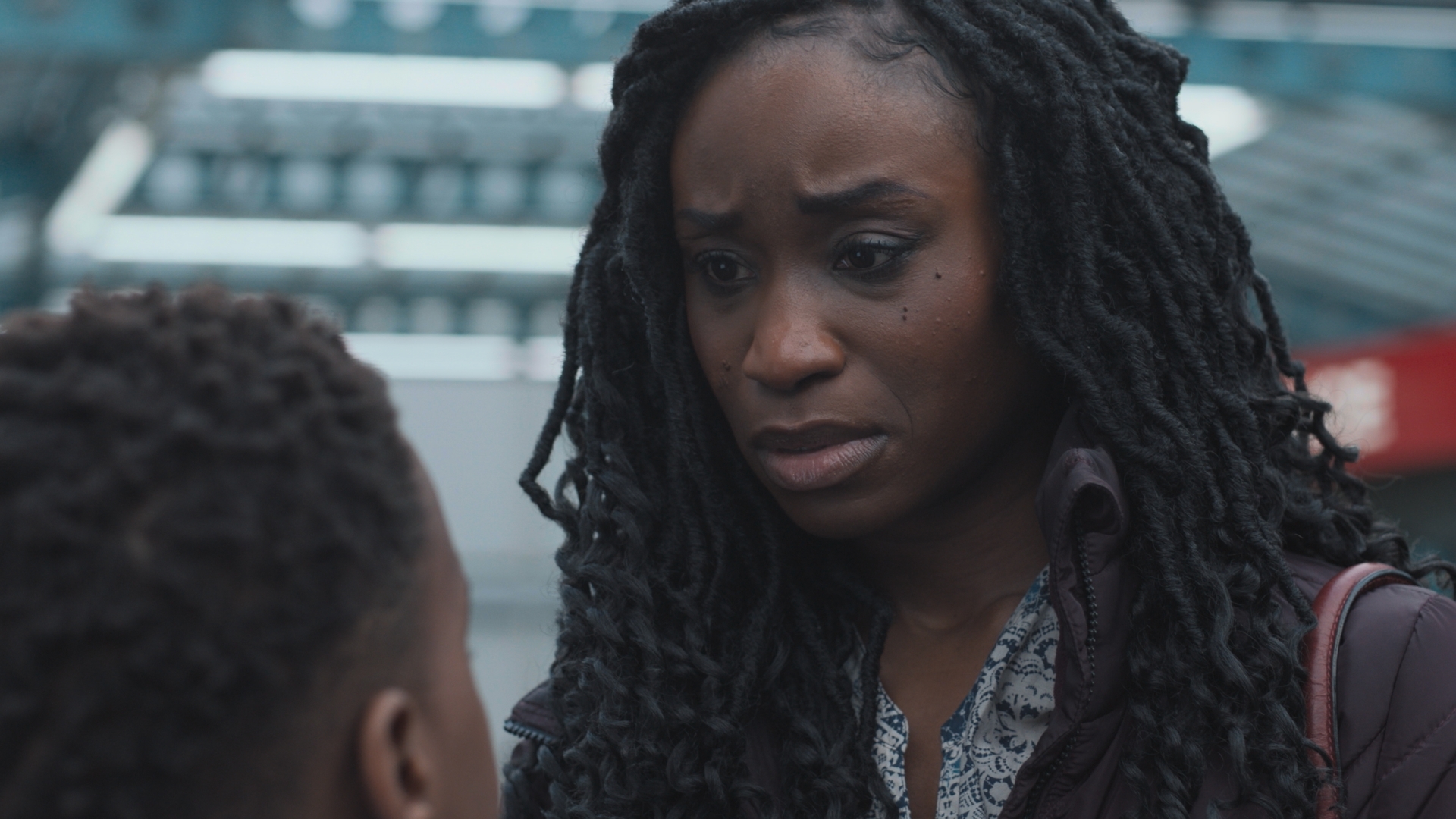 Ngozi with her young son Obi outside Holby ED at the end of her shift. She is wearing a dark coloured coat and her handbag can be seen on her shoulder.
