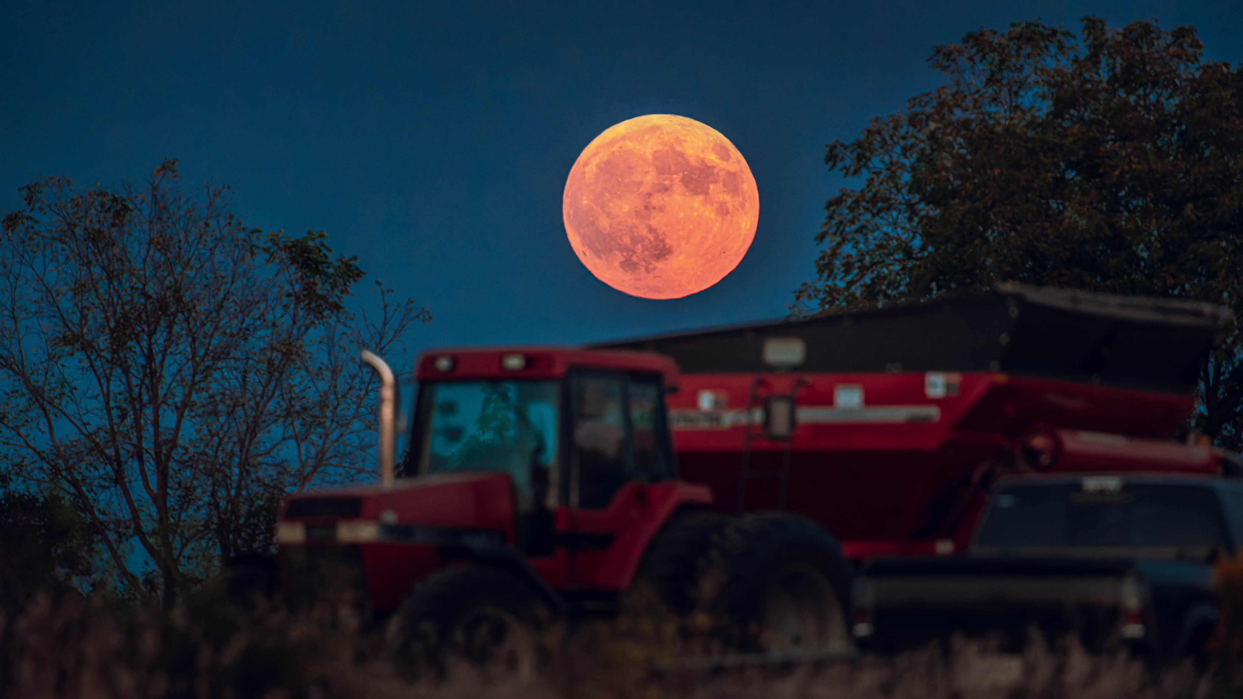 The full moon rises over a tractor