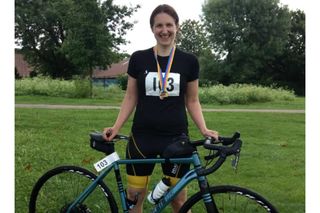 Dr Pippa Lally stands smiling behind a bike with greenery in the background