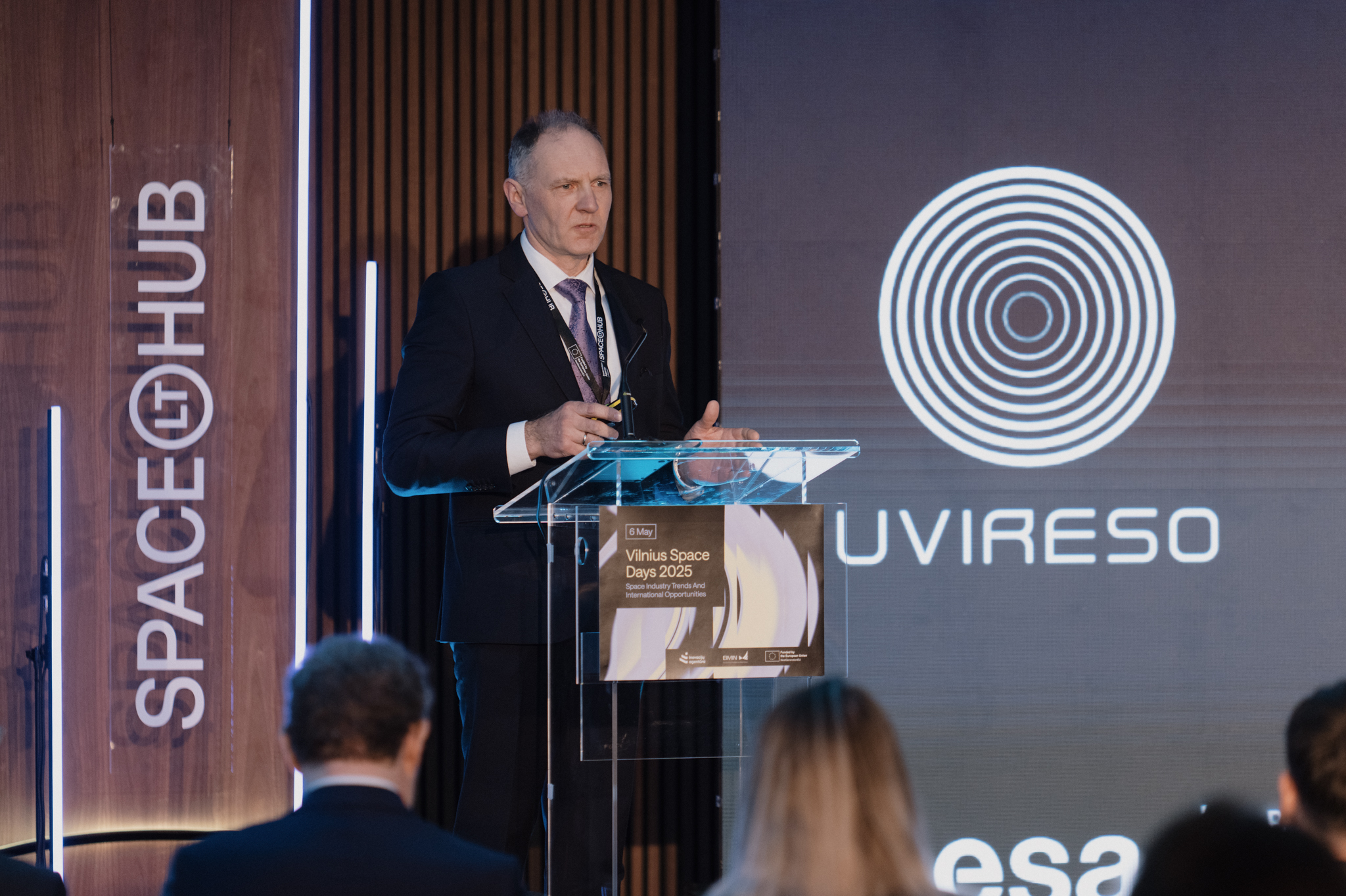 A person standing at a podium. in the background, it says "uvireso in space."