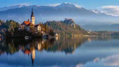 An evening shot of Lake Bled with snow-capped mountains in the background