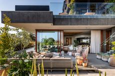 the exterior of a modern home with a large patio sofa and plants in pots