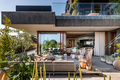 the exterior of a modern home with a large patio sofa and plants in pots