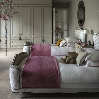 neutral bedroom with chandelier, matching beds and cupboard