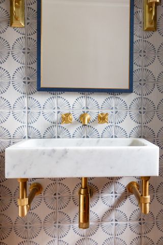 Close-up of white marble sink with gold hardware