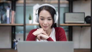 Woman with headphones on looking at laptop screen