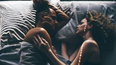 Woman and man lying together in bed as sunlight comes through blinds, representing sex and menopause