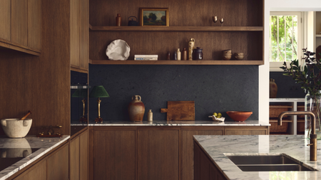 beautiful open plan kitchen with wooden cabinetry, a waterfall edge marble island and black tiled backsplash