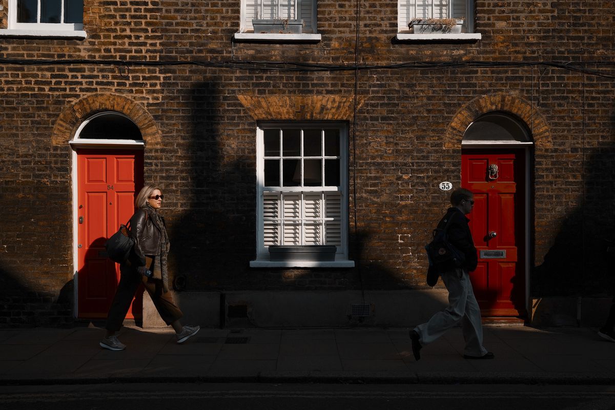 London street photo of people walking down old street in bright sunlight with strong shadows cast on the wall, taken with the Sigma BF camera and Sigma 35mm F2 DG lens