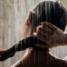 best hard water beauty products - woman in shower wringing out her hair 