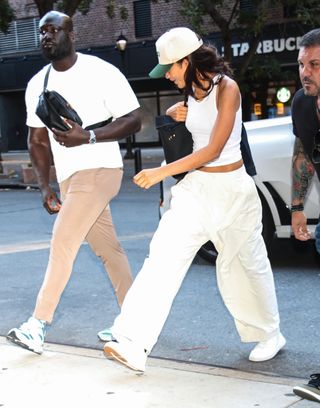 Zendaya wearing a baseball cap, a tank top, baggy pants, and white sneakers