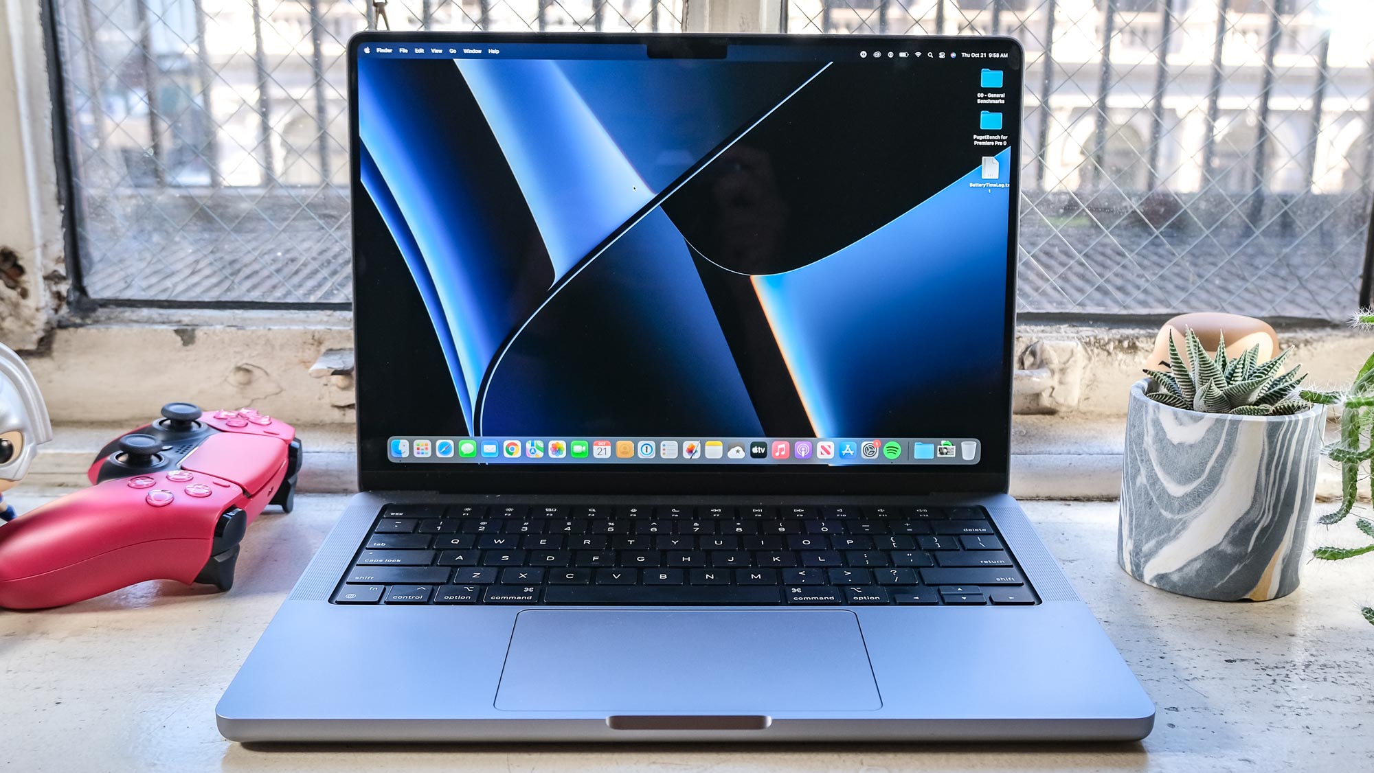 The MacBook Pro 2021 (14-inch) open to the desktop with a metallic blue background