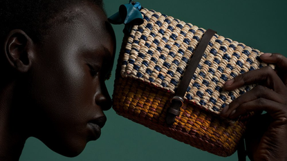 black owned fashion brands: woman holding a woven raffia bag to her head