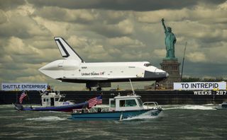 Atop a barge on Wednesday, June 6, 2012, the space shuttle Enterprise was towed on the Hudson River past the Statue of Liberty on its way to the Intrepid Sea, Air and Space Museum, where it will be permanently displayed.
