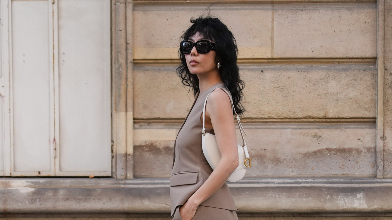 woman with cool tousled hair walking down the street wearing a beige waistcoat and sunglasses - Best hair creams 