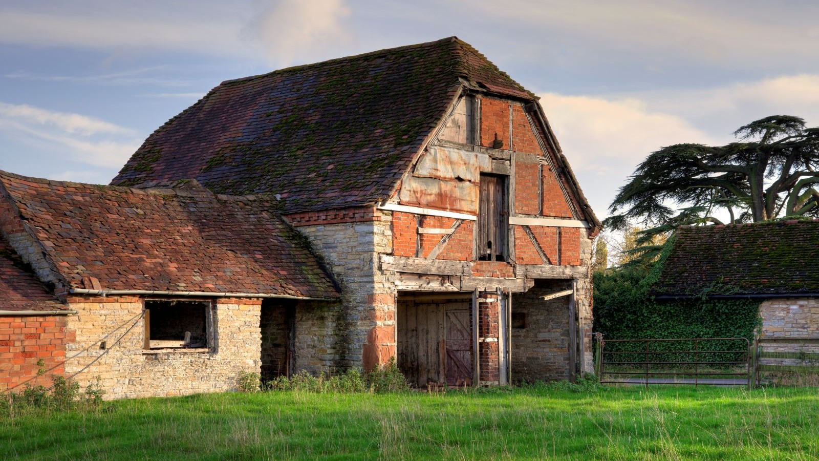 An old barn with hipped roof and red brick on the exterior