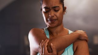 a woman holding her elbow and shoulder