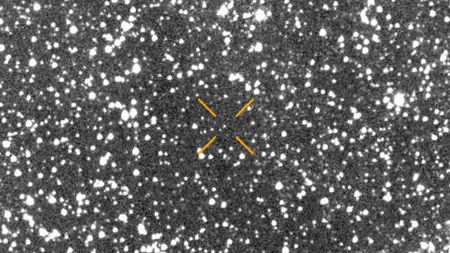 A blurry picture of stars with arrows pointing to where a comet is