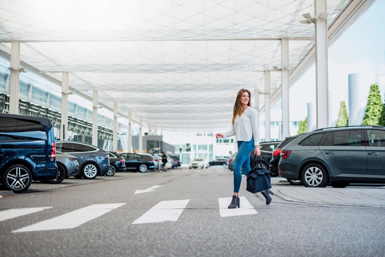 Young woman with luggage crossing at an airport zebra crossing