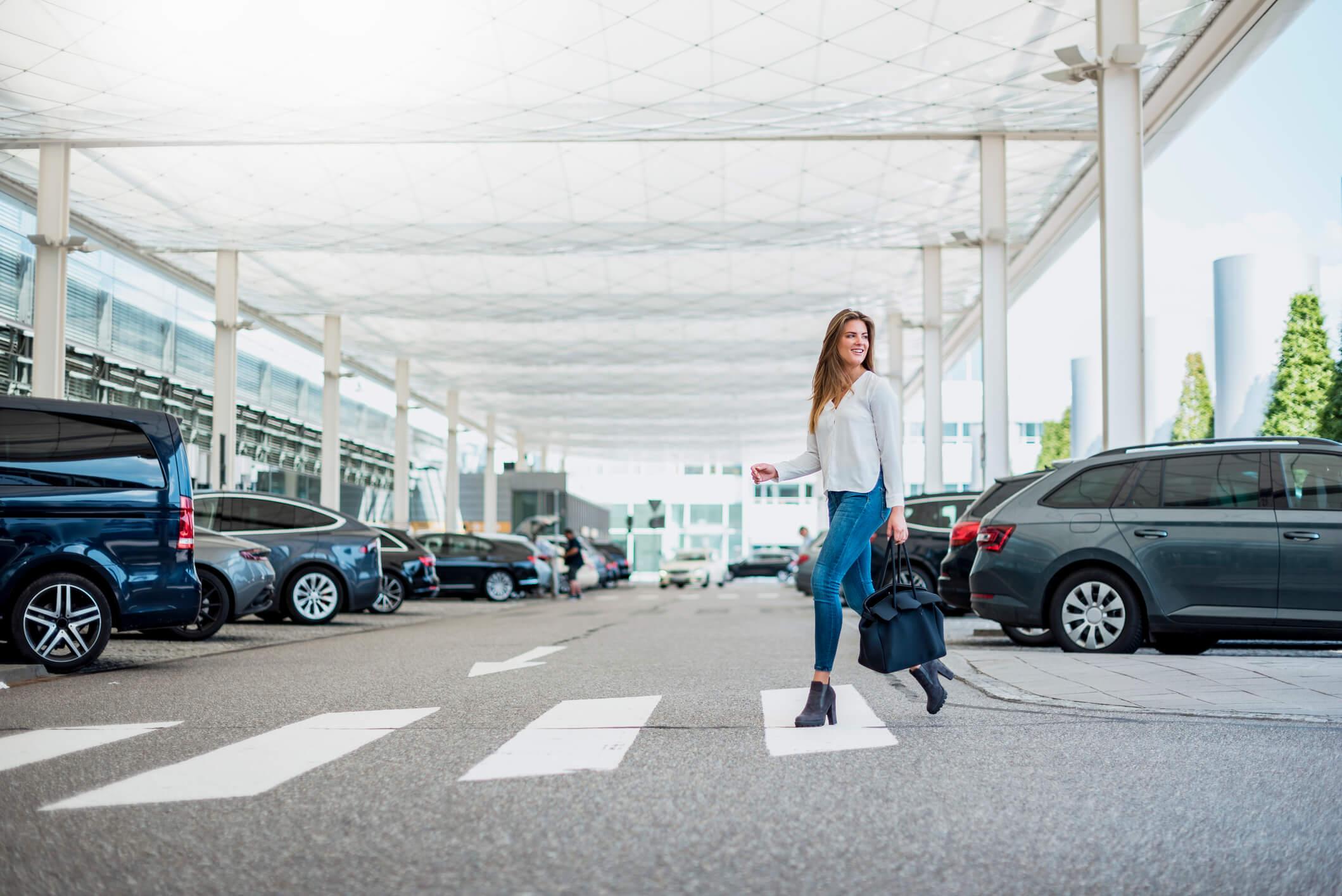  Young woman with luggage crossing at an airport zebra crossing 