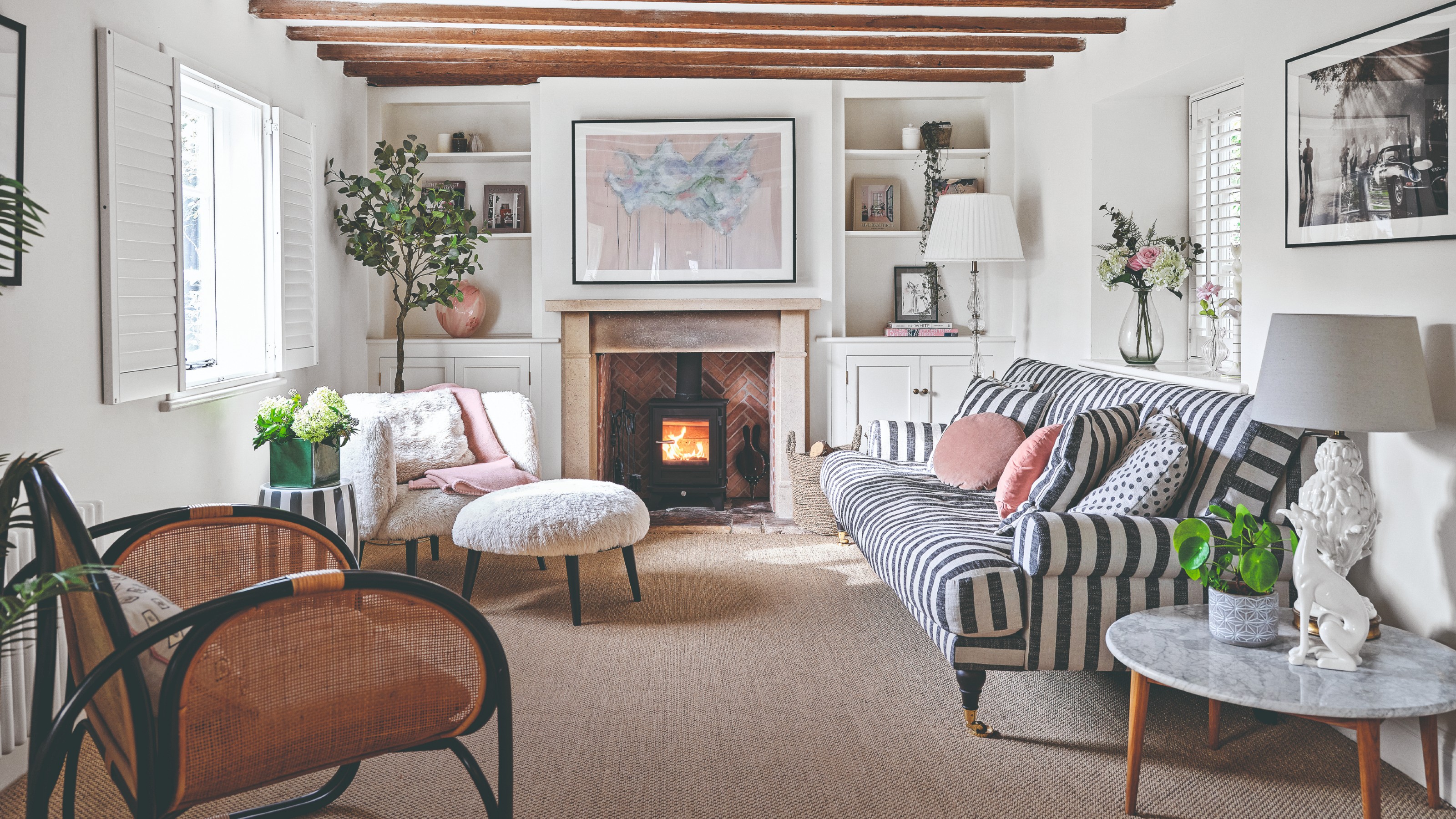 A white-painted living room with a rattan accent chair and a striped sofa