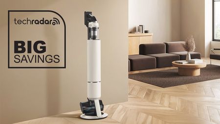 Samsung Bespoke AI Jet Lite vacuum cleaner standing in its dock in a home, with "Big Savings" text in black.