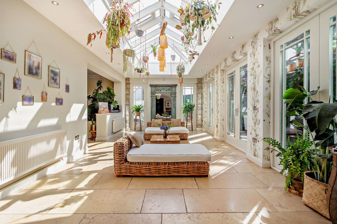 A garden room/orangery with beds/sitting chairs and plants hanging from the ceiling
